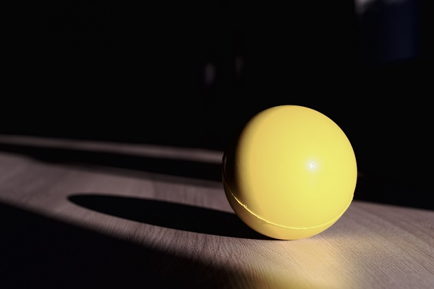 balle jaune posée sur une table éclairée de côté
