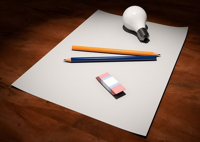Une feuille avec deux crayons, une gomme et une ampoule